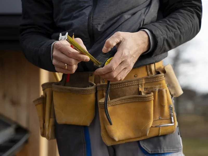 Hausmeister mit Werkzeuggürtel bei der Arbeit in Siegen